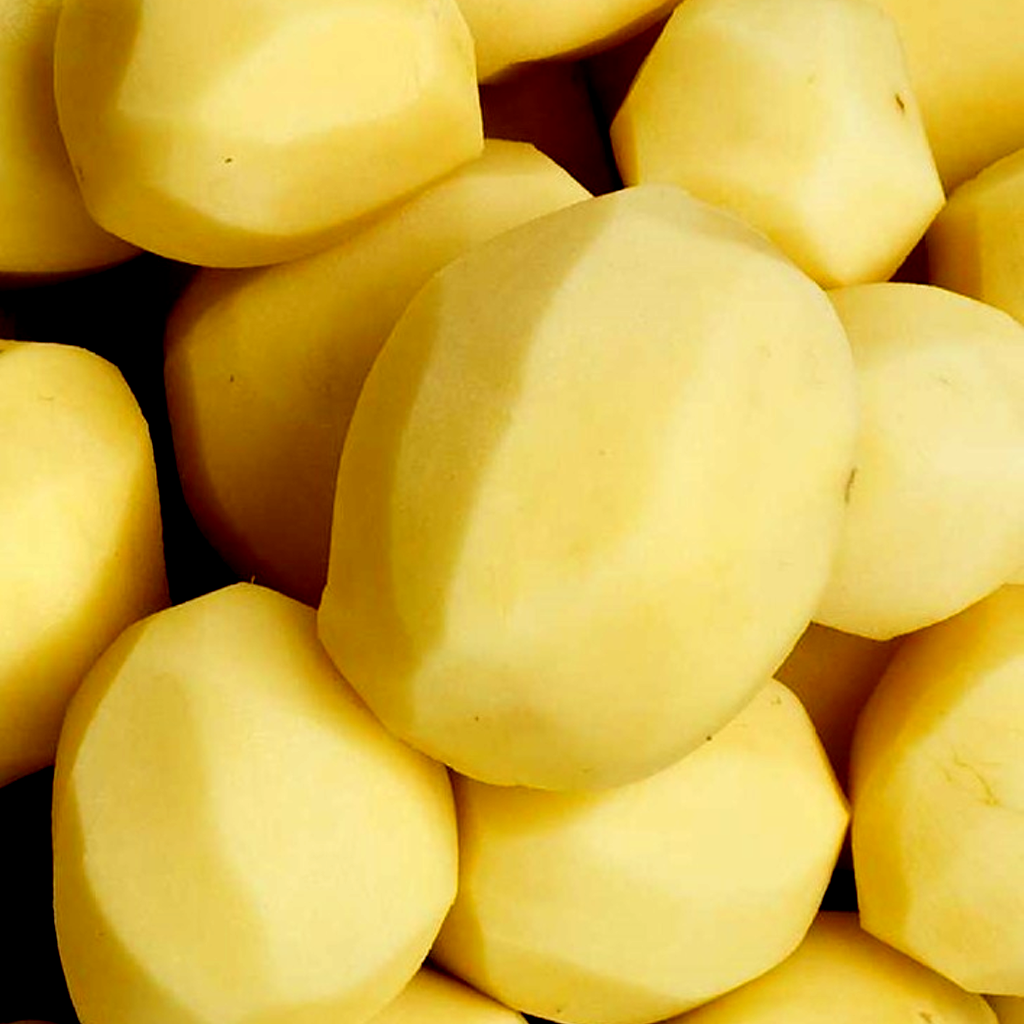The image shows a close-up of several peeled potatoes. The potatoes are smooth, with their skins removed, revealing their pale yellow or creamy white flesh. They are of various sizes but are uniformly peeled, giving a clean and neat appearance. The background is filled with the potatoes, emphasizing their quantity and preparation for cooking.